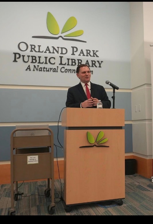 Steve Beaman speaking at a podium at Orland Park Public Library